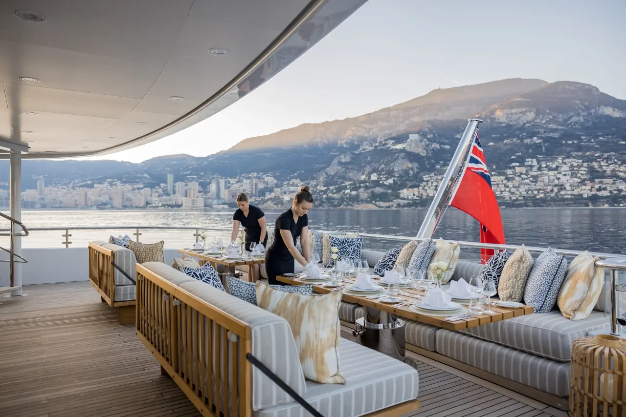 Two stewardesses setting a table on an aft deck